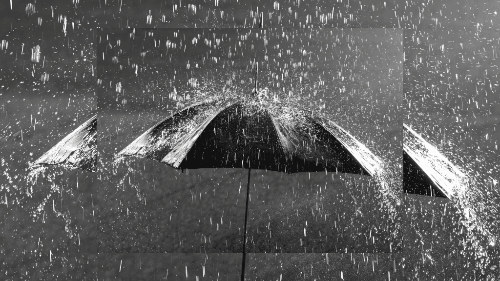 Guarda-chuva preto visto de cima sendo atingido por forte chuva, com gotas respingando ao redor, simbolizando proteção, limpeza emocional e o significado de sonhar com chuva.